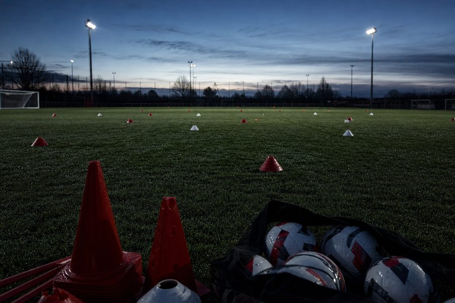 Training cones and a bag of footballs on an empty youth pitch at first light