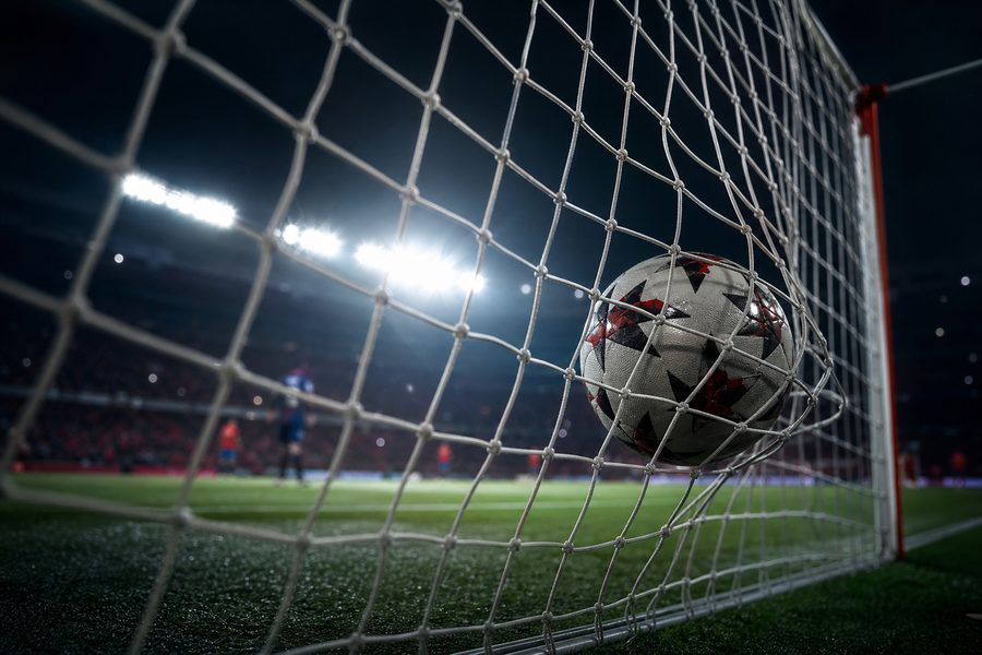 Inside of a goal net bulging where a ball has just struck it