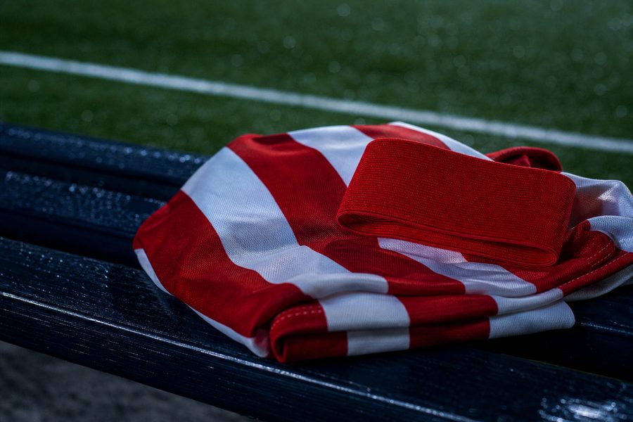 Plain captain's armband resting on a folded red and white striped shirt